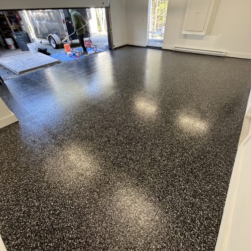 Garage floor finished with Raven flake epoxy, showcasing a bold black and gray speckled pattern for a sleek and durable look
