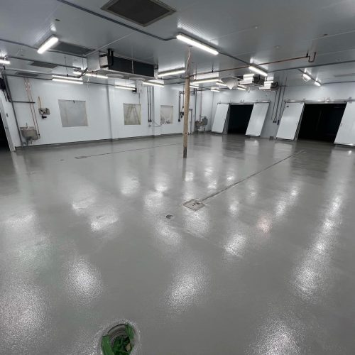 Commercial kitchen floor finished with Stout epoxy coating, featuring a light grey, durable design for a professional and resilient surface