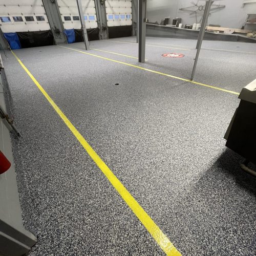 Fire hall floor coated with Orbit flake epoxy, featuring a durable finish with a blend of gray, blue, and black flakes for a professional and resilient look